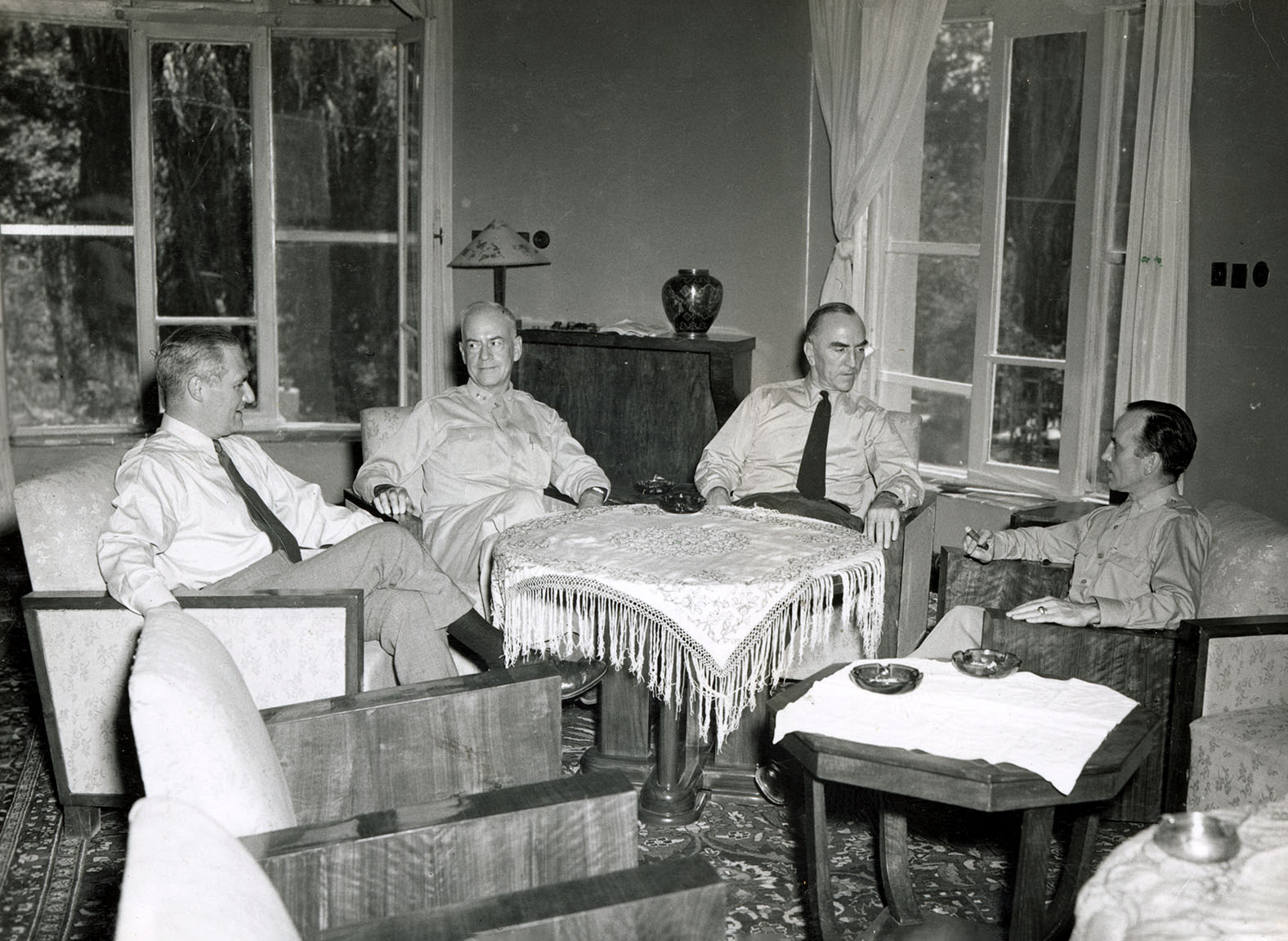 Four men sit in upholstered chairs in a large room